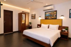 a bedroom with a large bed with white sheets at The Regatta Landing in Alleppey