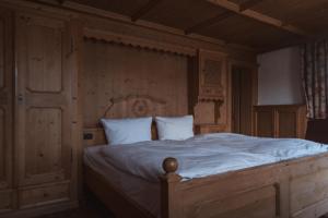 a bedroom with a large wooden bed with white sheets at Superseegarten in Bad Wiessee