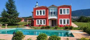 a large red house with a swimming pool in front of it at Villa AVRA in Drama