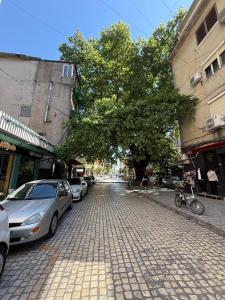 a cobblestone street with parked cars and a tree at Valentino Apartments in Shkodër