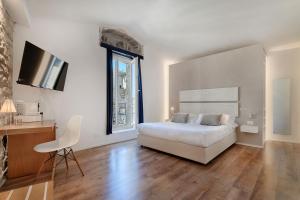ein Schlafzimmer mit Bett, Schreibtisch und Fernseher in der Unterkunft Iblaresort Boutique Hotel in Ragusa