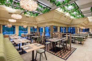 a restaurant with tables and chairs and chandeliers at Danubius Hotel Bük in Bük