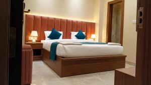 a bedroom with a large bed with blue pillows at The Infinity Hotel in Kānpur +12 photos