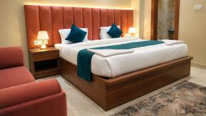 a bedroom with a large bed and a chair at The Infinity Hotel in Kānpur