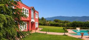 a red house with a swimming pool next to a yard at Villa AVRA in Drama