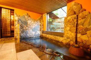 a room with a pool of water in a stone wall at Kinosaki Tenboen in Toyooka