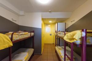 a room with three bunk beds and a yellow door at Alberg Núria Xanascat in Queralbs
