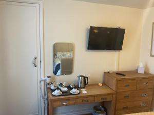 a bedroom with a dresser with a mirror and a tv at Ivy House B&B in Dolgellau