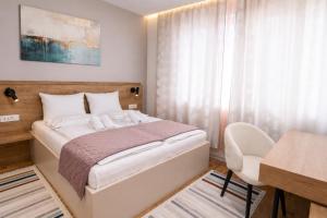 a bedroom with a bed and a desk and a chair at Urban Getaway Sarajevo with Free Parking in Sarajevo