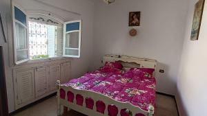 a bedroom with a bed with pink sheets and a window at Charmante maison plage in Soliman