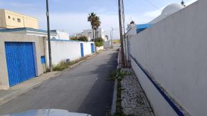 an empty street next to a white fence at Charmante maison plage in Soliman