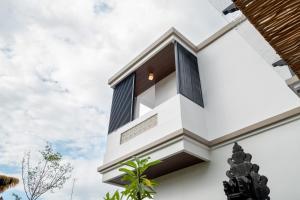 a white house with black windows and plants at Gumitish Residence Singaraja in Singaraja