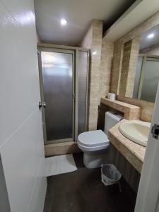 a bathroom with a toilet and a shower and a sink at Ralph Anthony Suites Hotel in Manila