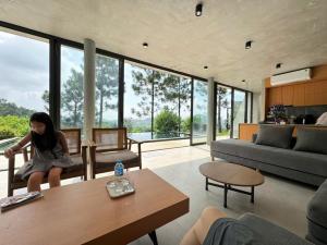 a woman sitting on a couch in a living room at Pine Hill Villa 3 Vì in Ba Vì