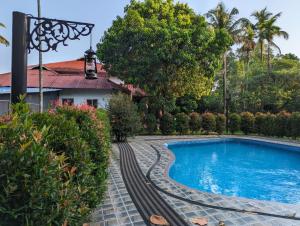 a swimming pool in front of a house with a resort at Peninsular wood Resort in Thattakād +23 photos