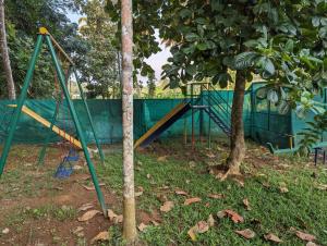 a playground in a park next to a tree at Peninsular wood Resort in Thattakād