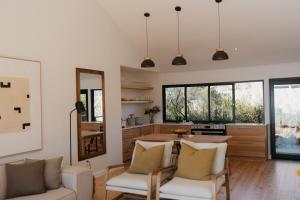 a living room with two white chairs and a kitchen at Ocean's Edge - Private Nature Reserve in George