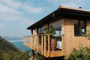 a wooden house on a hill with a view of the ocean at Ocean's Edge - Private Nature Reserve in George