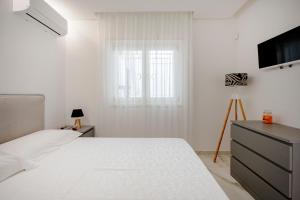 a white bedroom with a bed and a television at GuestHost - Lume di Mare in Faccia di Trippa +28 photos