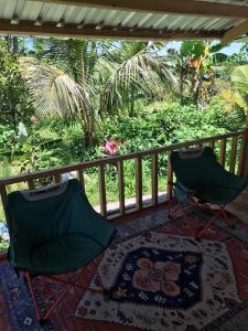 two green chairs sitting on a porch with a rug at Konbayan Forest Stay in Bayan