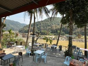 a patio with tables and chairs and a view of a river at PAKBENG SUNSET DORM Room in Pakbeng