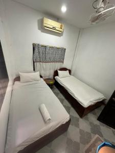 a room with two beds in a room with a fan at PAKBENG SUNSET DORM Room in Pakbeng +1 photo