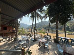 a patio with tables and chairs and a view of a river at PAKBENG SUNSET DORM Room in Pakbeng
