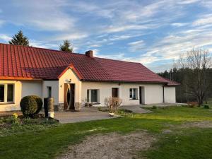 a white house with a red roof at Cozy Forest House in Jonkowo