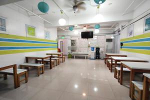 a room with tables and benches and a tv in it at Yuj Inn Pasay in Manila