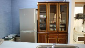 a kitchen with a refrigerator and a wooden cabinet at Sakuraya 亀島店 in Nagoya