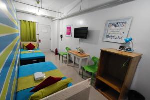 a room with two beds and a tv and a desk at Yuj Inn Pasay in Manila