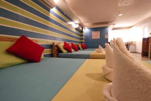 a room with a row of beds with colorful pillows at Yuj Inn Pasay in Manila