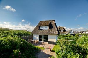 a house with a thatched roof with a patio at Lütt Hüs 1 in Wenningstedt