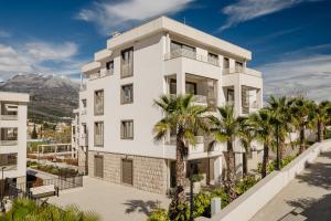 a white building with palm trees in front of it at Adriatic Sea Escape B20 in Herceg-Novi