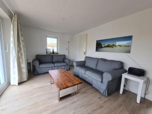a living room with two couches and a table at Lütt Hüs 1 in Wenningstedt +3 photos