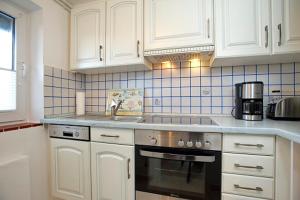 a kitchen with white cabinets and a stove top oven at Lütt Hüs 1 in Wenningstedt