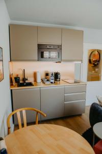 a kitchen with white cabinets and a table at sleepArt beach in Celle