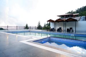 a swimming pool with a house in the background at DN Resort Dharamshala in McLeod Ganj
