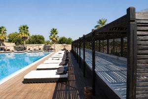 a swimming pool with chaise lounges on a wooden deck at Hotiday Otranto Baia Resort in Otranto