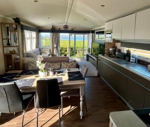 a kitchen and living room with a table and a couch at Wild Thistle static Caravan in Kirkcolm