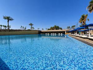 a large swimming pool with blue water and palm trees at Hotiday Otranto Baia Resort in Otranto +16 photos