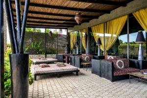a patio with couches and tables and yellow curtains at Hotiday Otranto Baia Resort in Otranto