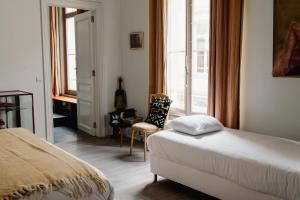 a bedroom with a bed and a chair and a window at Les Chambres du Vaudeville in Brussels