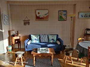 a living room with a blue couch and a table at Gîte MAÏ - Classé 3 étoiles in Dieppe