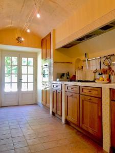 a large kitchen with wooden cabinets and a door at Maison dans un parc in Parentignat