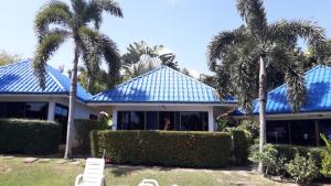 a house with a blue roof and palm trees at bungalow with swimming pool in Rawai Beach
