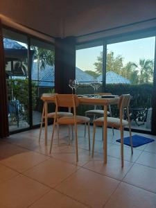 a dining room with a table and chairs and windows at bungalow with swimming pool in Rawai Beach