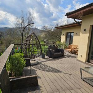 a patio with a swing and chairs on a house at Forest House Doftana in Teşila +64 photos
