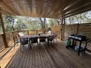 a deck with a table and chairs and a grill at Le Beau Vezé in Carqueiranne