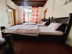 two twin beds in a room with a window at Hunza Backpackers Inn in Hunza Valley